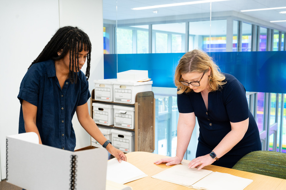 two Tech librarians working with paper on a desk