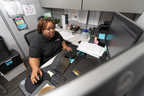 Tech employee sitting at their desk with 3 monitors